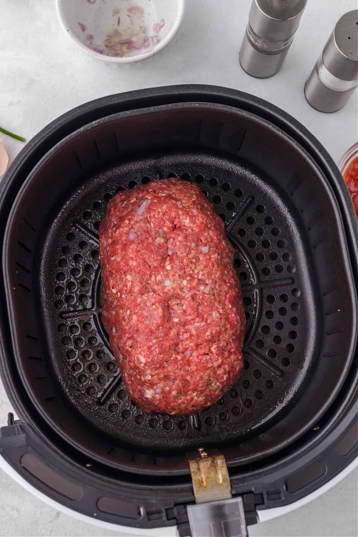 food in an air fryer basket, with meatloaf