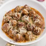 cooked meatballs in a white pan with melted cheese on top
