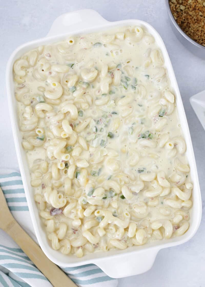 uncooked mac and cheese with jalapeno and bacon in a large white casserole dish