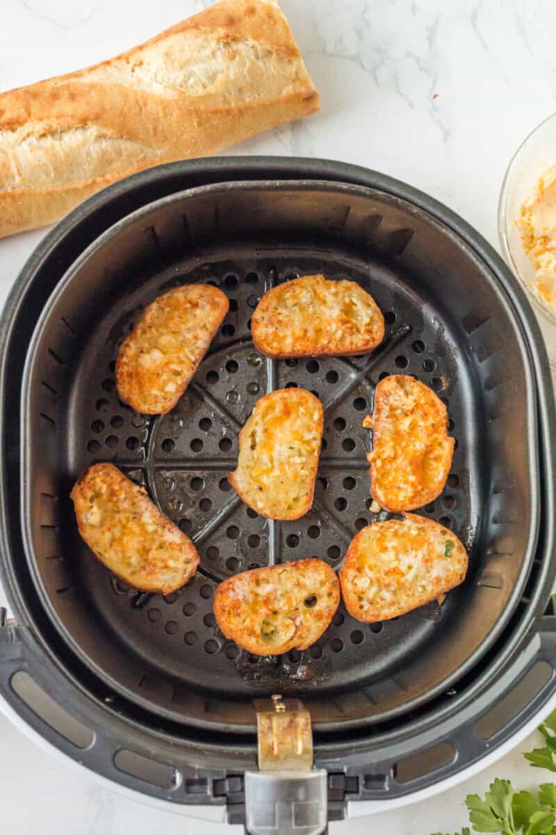 cooked garlic toast pieces in a black air fryer basket.