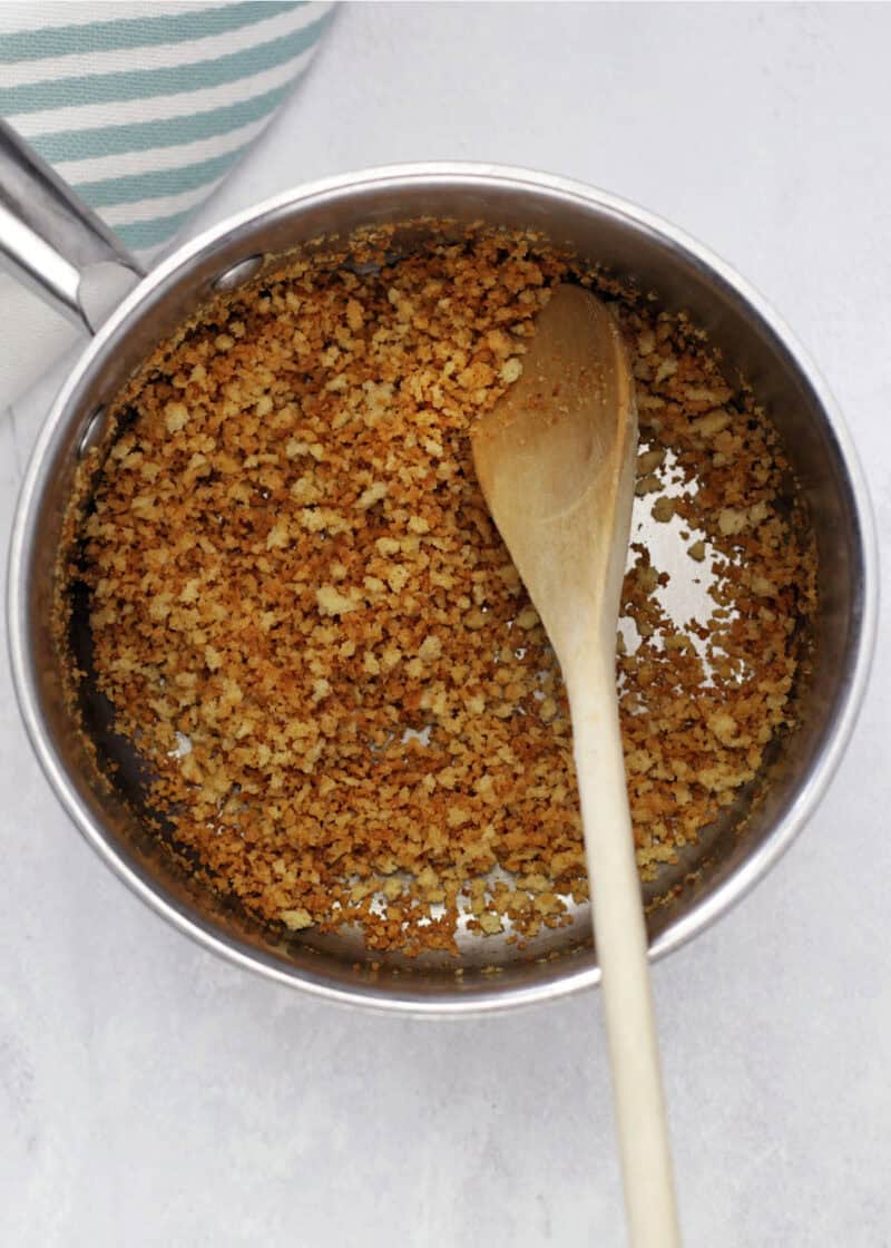 cooked panko breadcrumbs in a large stainless steel pot with a wooden spoon