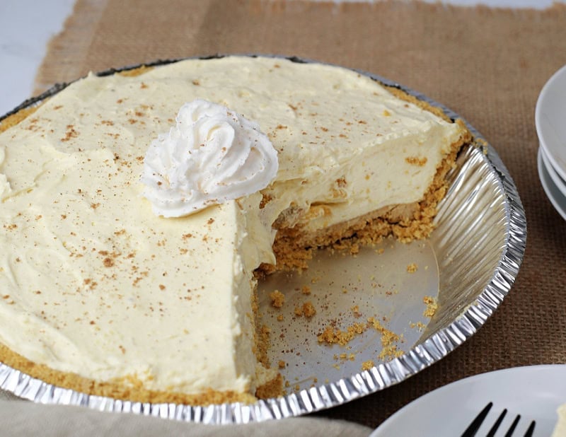 an eggnog pie with whipped cream on top in an aluminum pie plate.