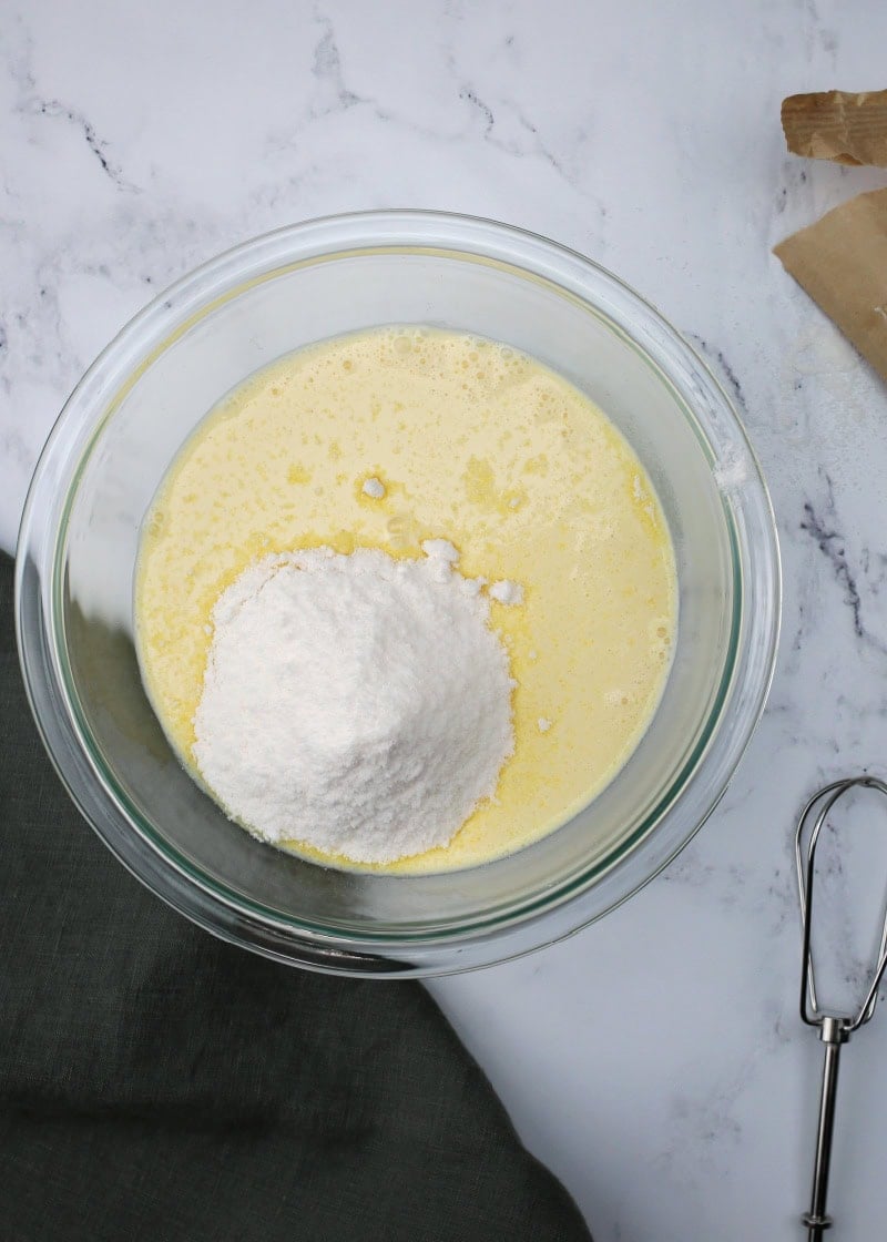 a glass bowl with a yellow pudding mixture in it and the beaters of an electric mixer beside it.