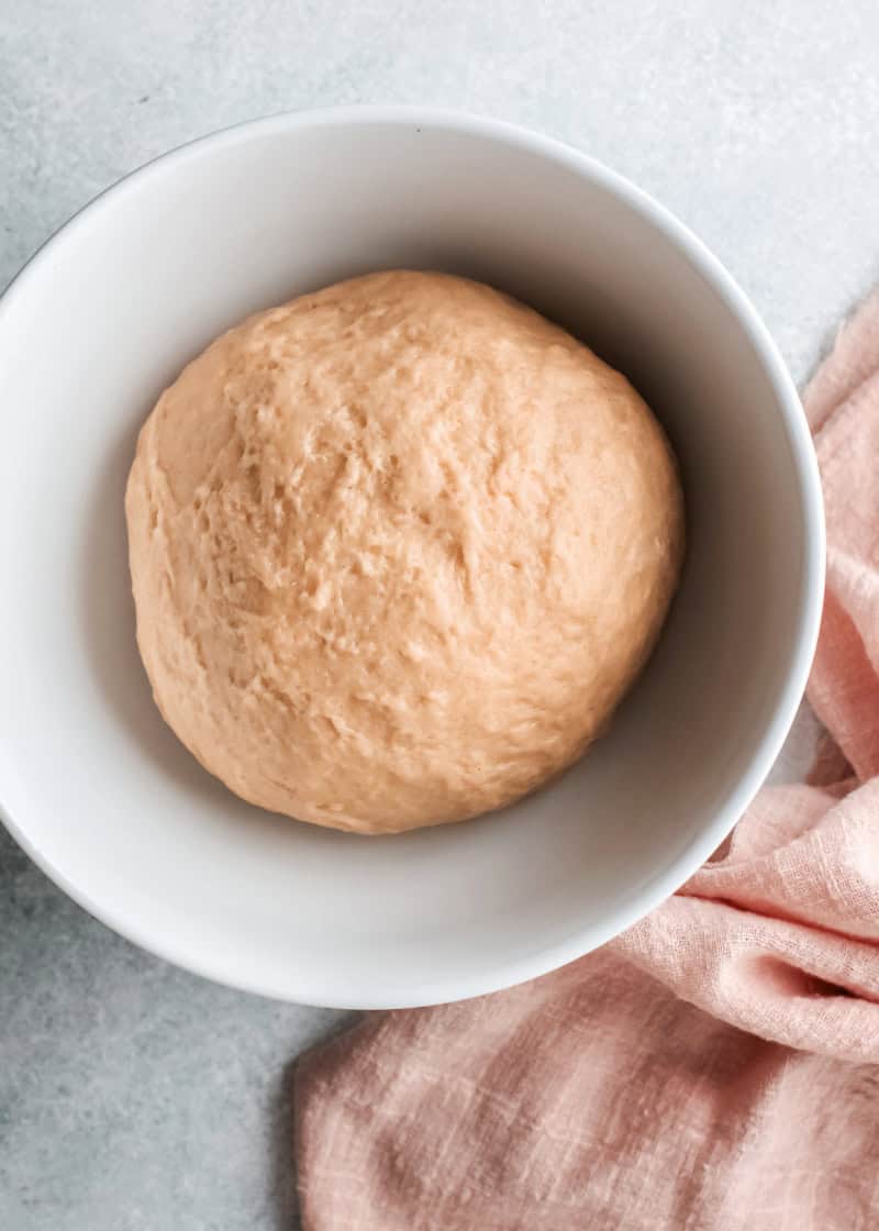 a ball of dough in a white bowl.