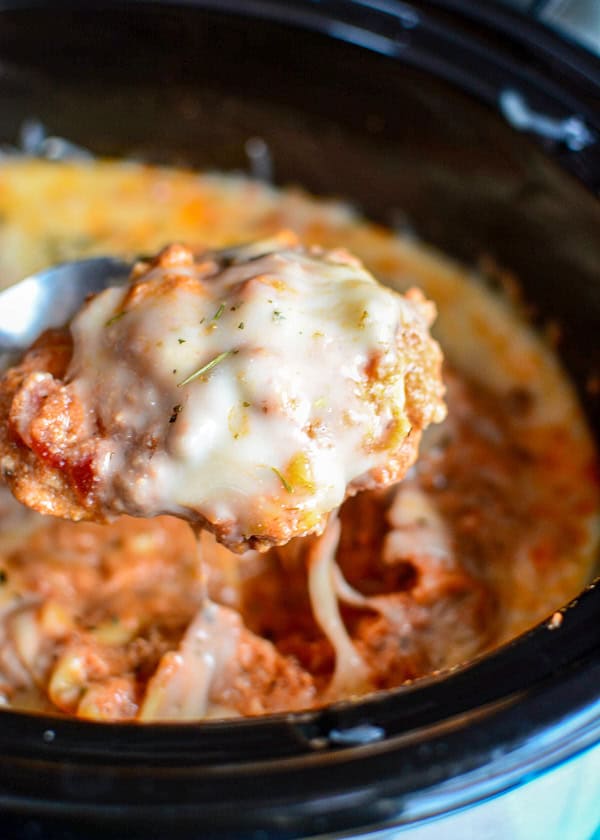 cheese and meat mixture being scooped out of a black crockpot.
