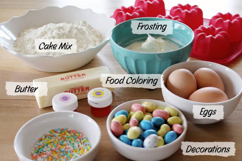 Ingredients on a table like cake mix, butter, icing, decorations and eggs.