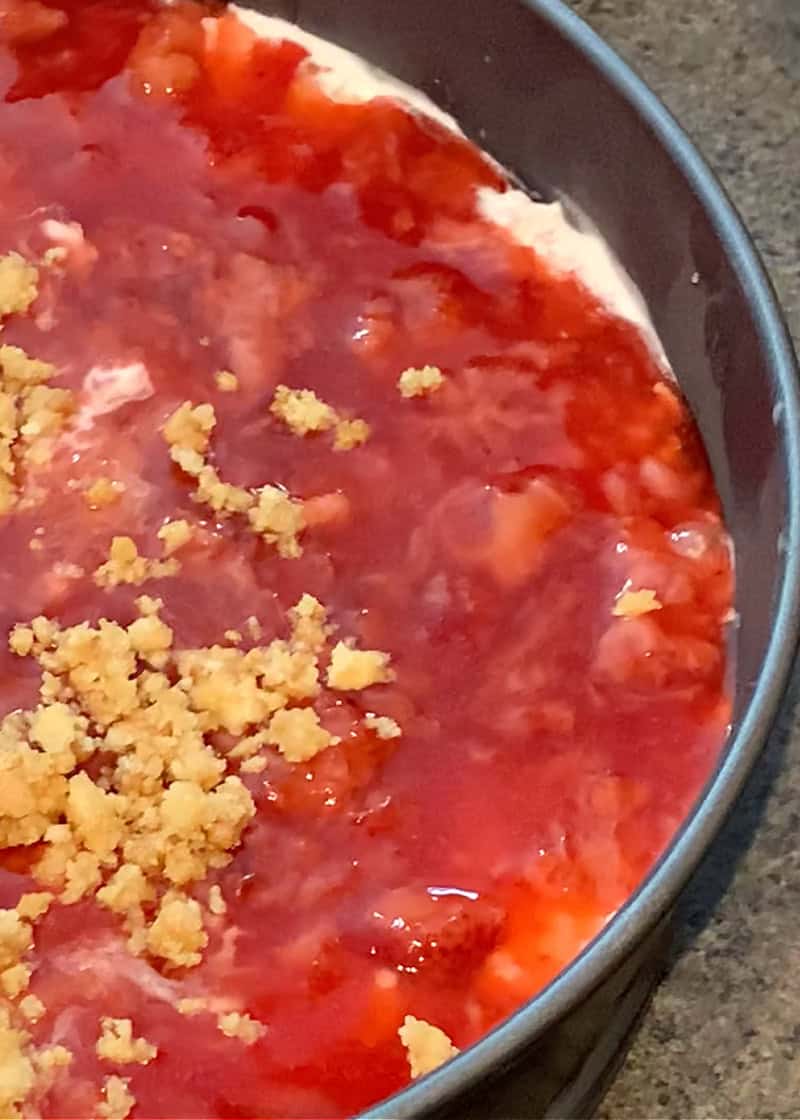 strawberry sauce and cookie crumble on top of ice cream spread into a spring-foam pan to make homemade ice cream cake.