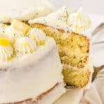 A slice of lemon poppy seed cake being cut from a whole cake.