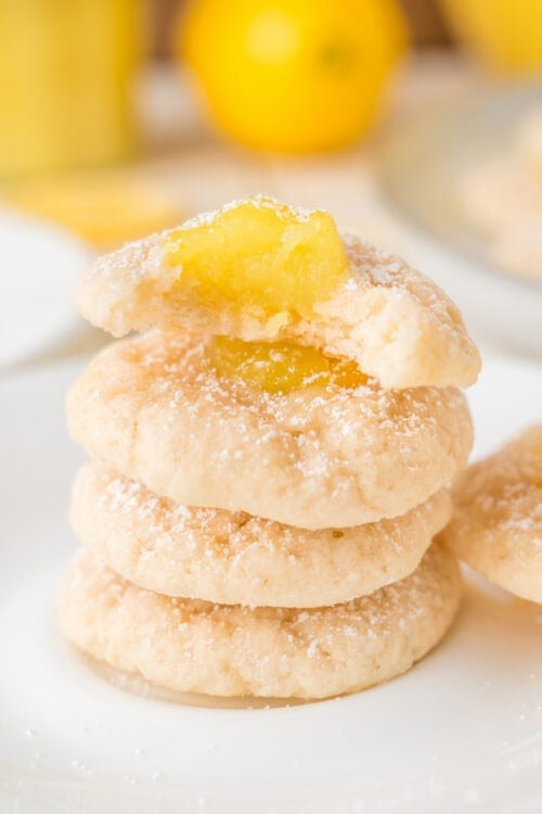 Lemon Thumbprint Cookies sprinkled with powdered sugar stacked on a white plate.