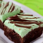a chocolate brownie with a green frosting on top drizzled with melted chocolate.