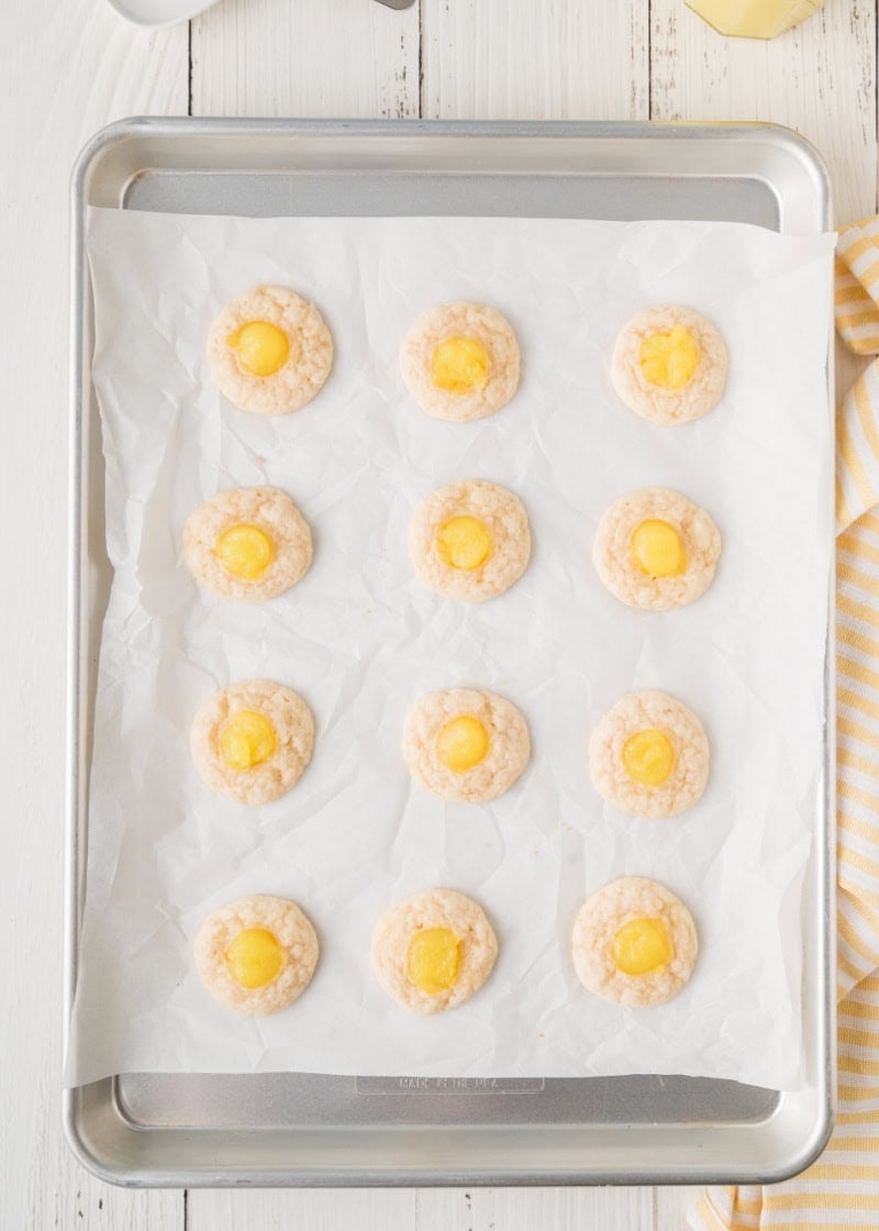 Baked lemon Thumbprint Cookies on a parchment paper lined baking sheet.