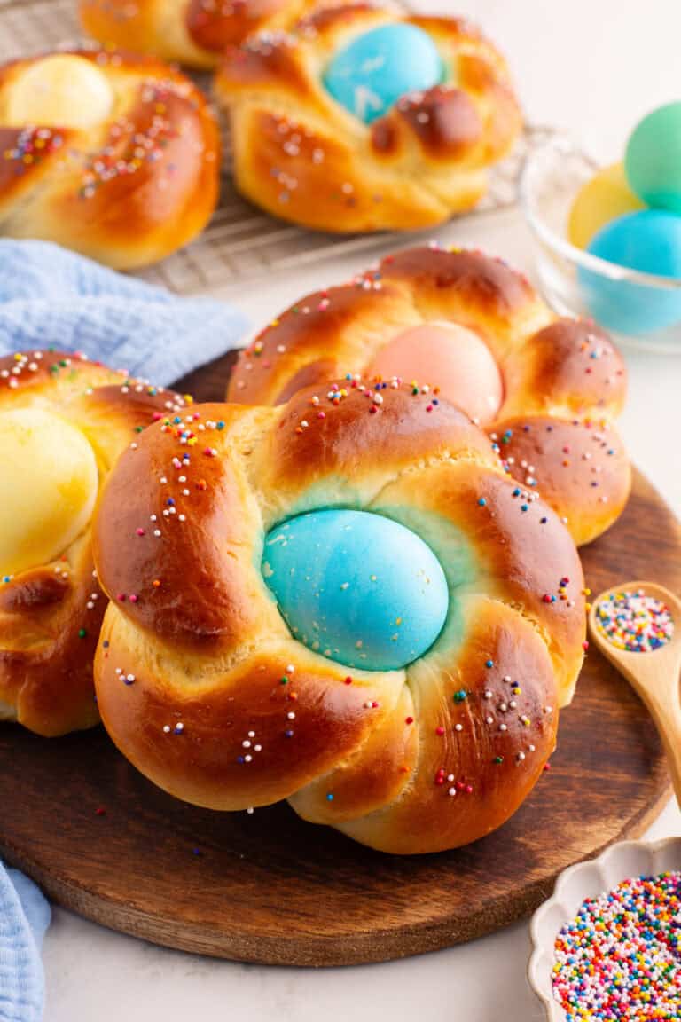 baked easter bread with colored sprinkles and a dyed egg in the middle.