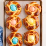 baked easter bread with colored sprinkles and a dyed egg in the middle.