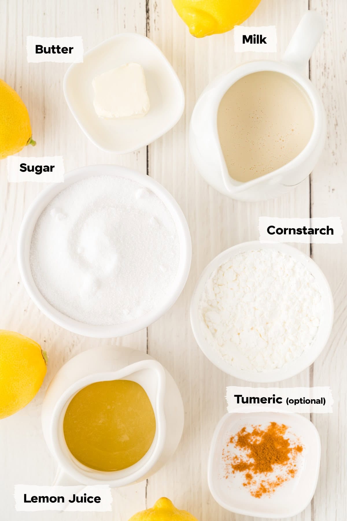 ingredients on a table to make lemon curd including sugar, butter, lemon juice, cornstarch and milk.