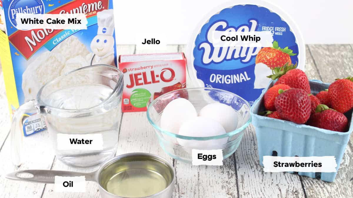 ingredients on a table to make strawberry poke cake with jello, box cake mix, water, eggs, and fresh strawberries.