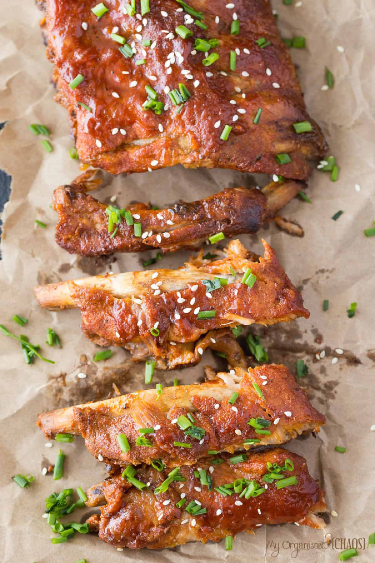 cooked ribs with bbq sauce, sesame seeds, and green onions on it.