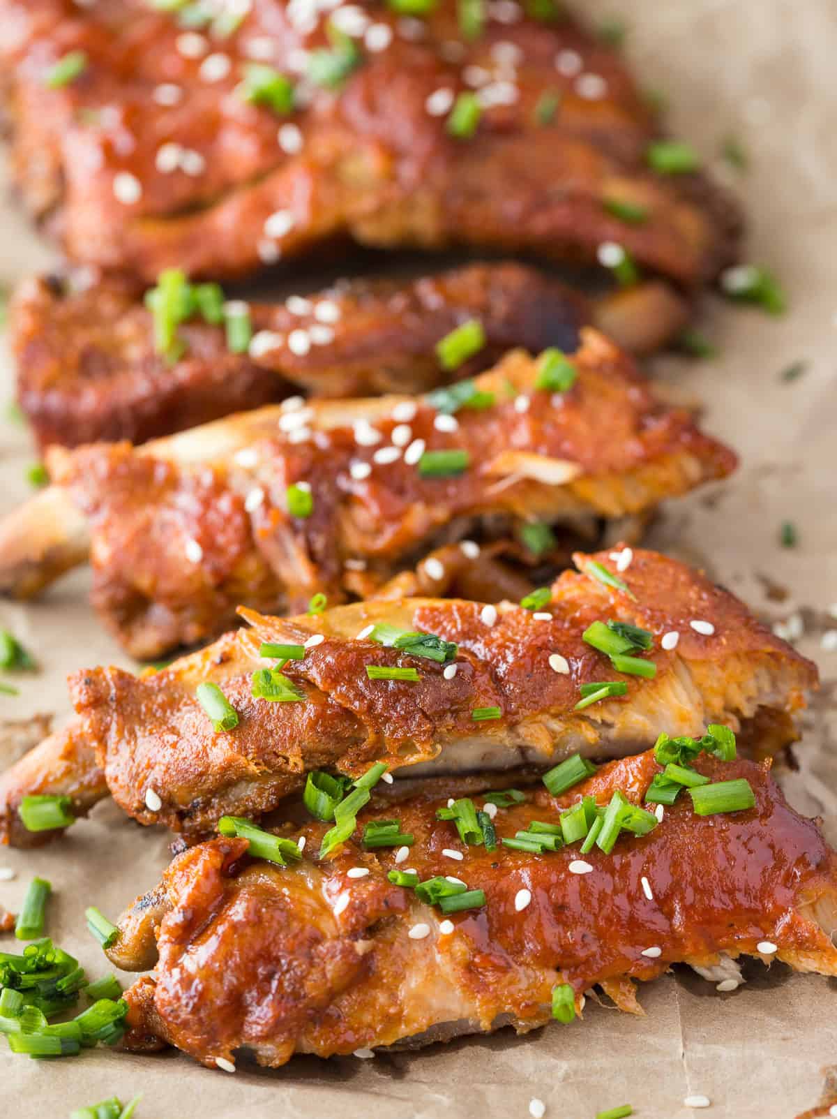cooked ribs with bbq sauce, sesame seeds, and green onions on it.