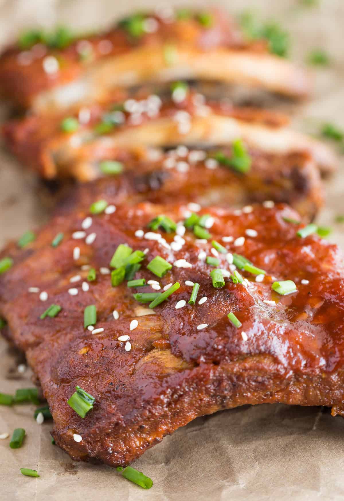 cooked ribs with bbq sauce, sesame seeds, and green onions on it.