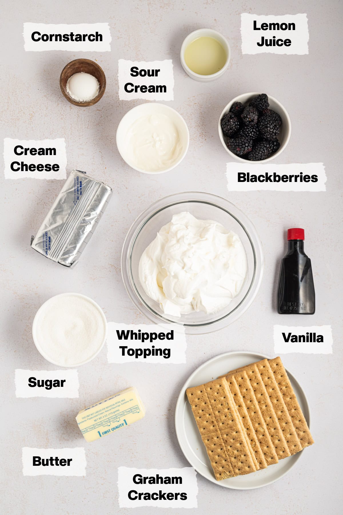 ingredients to make blackberry cream pie such as whipped topping, fresh blackberries, sour cream, lemon juice and graham crackers.