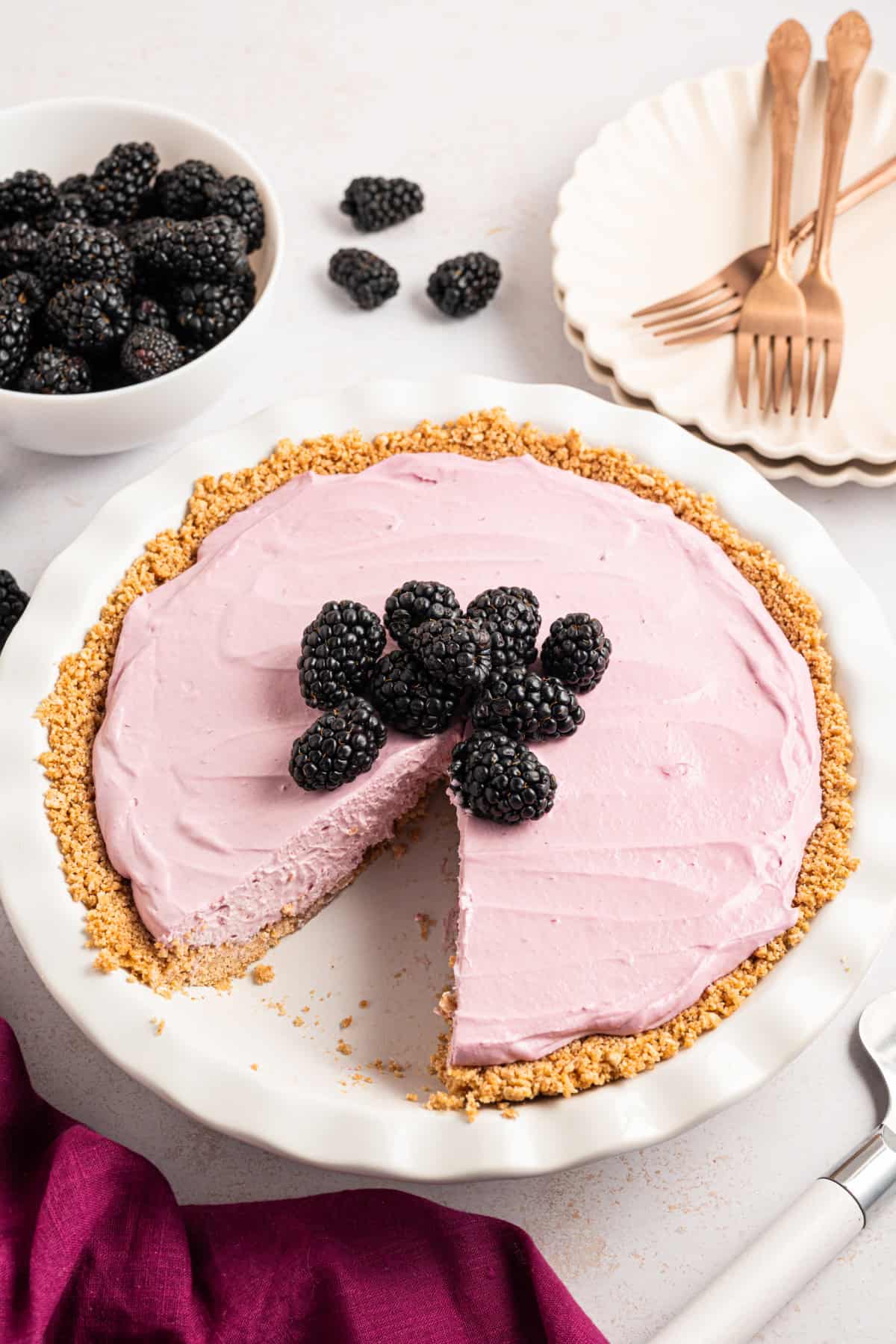 a Blackberry Cream Pie in a graham cracker crust with fresh blackberries on top, with a slice of blackberry cream pie out of it.
