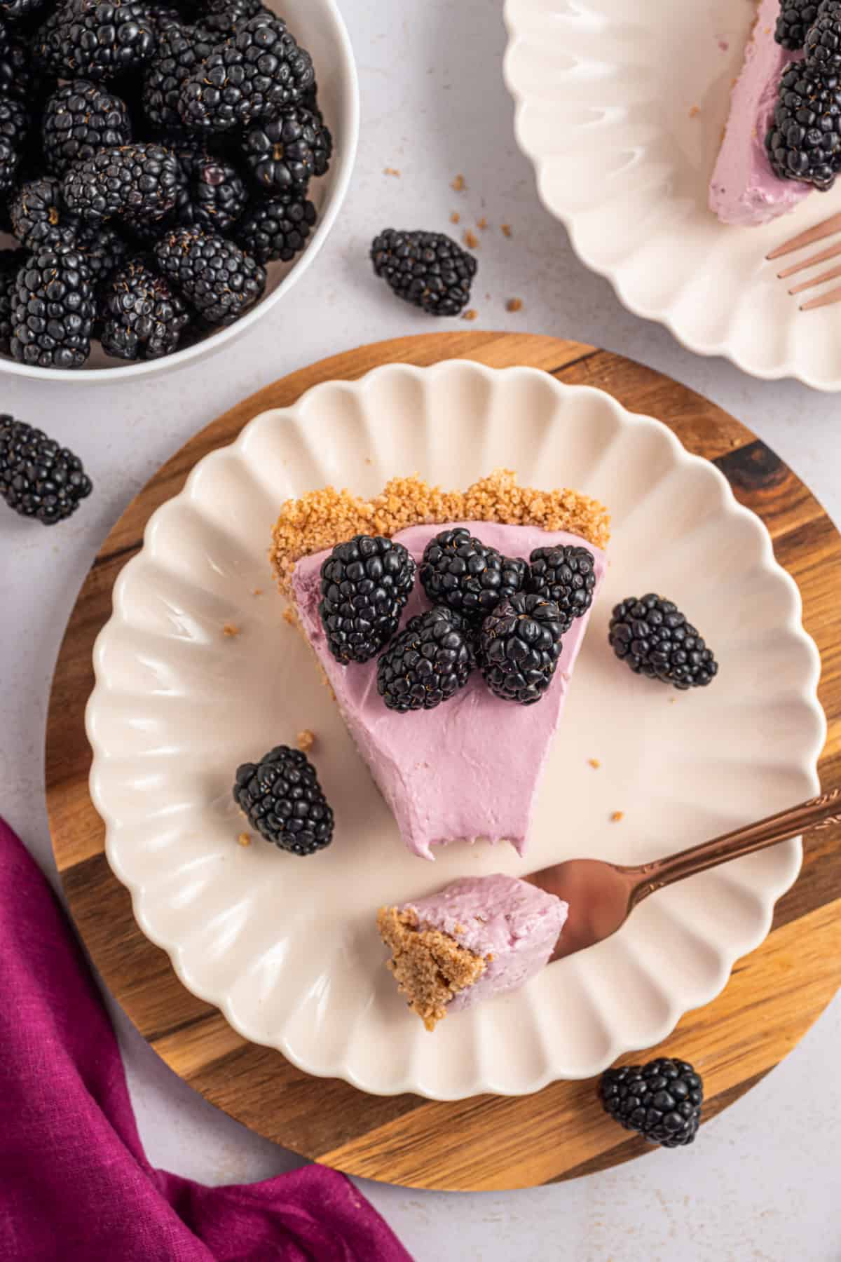 a slice of blackberry cream pie on a plate with fresh blackberries on top and beside it.