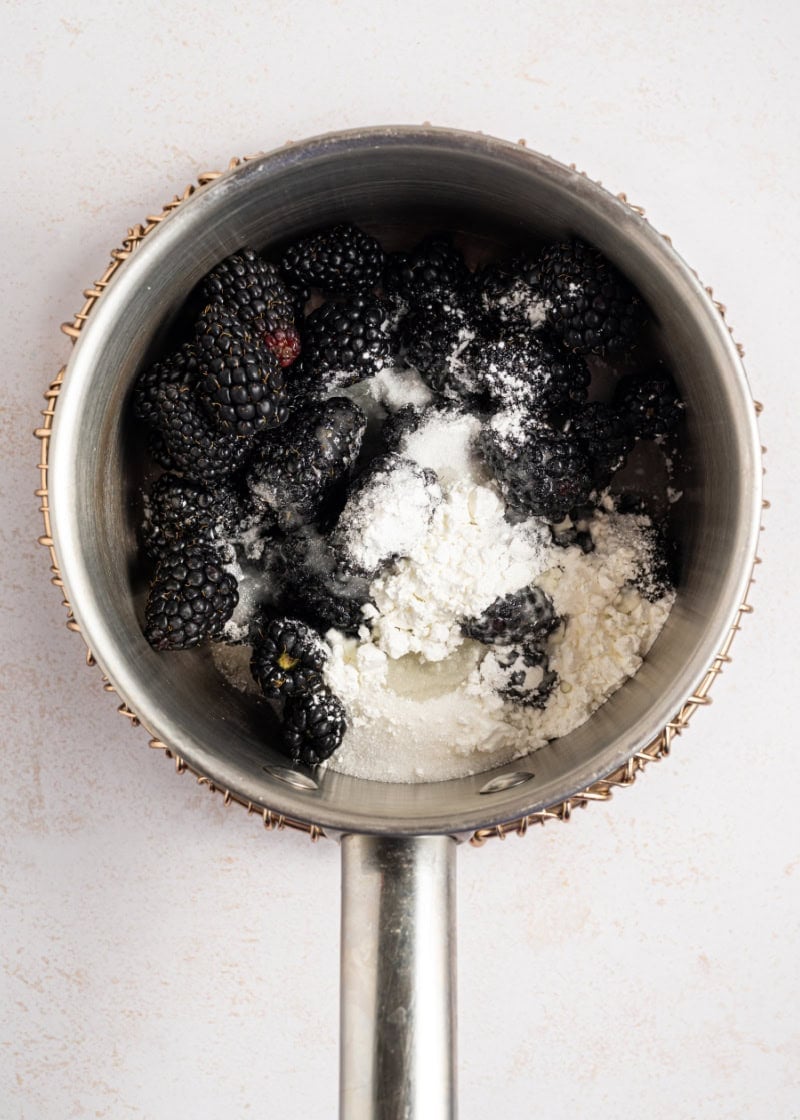 a small saucepan with fresh blackberries in it and flour.