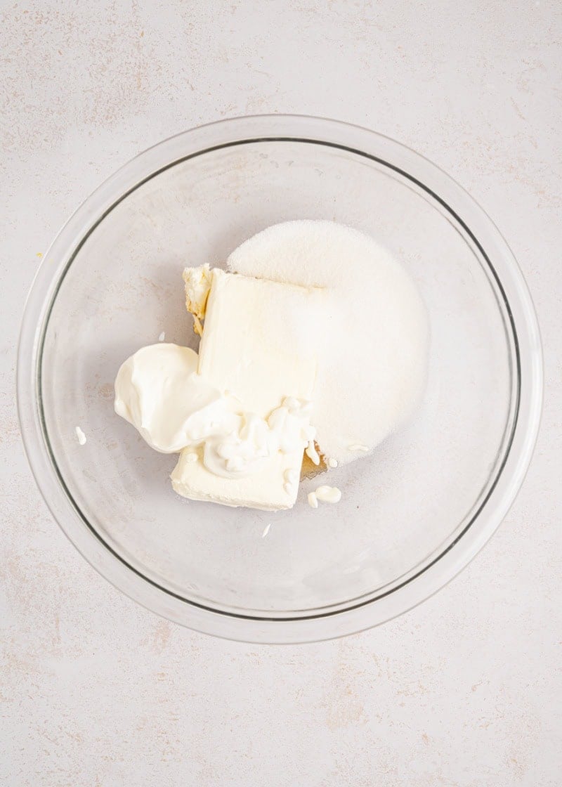 a glass bowl of cream cheese and sugar ready to be mixed together.