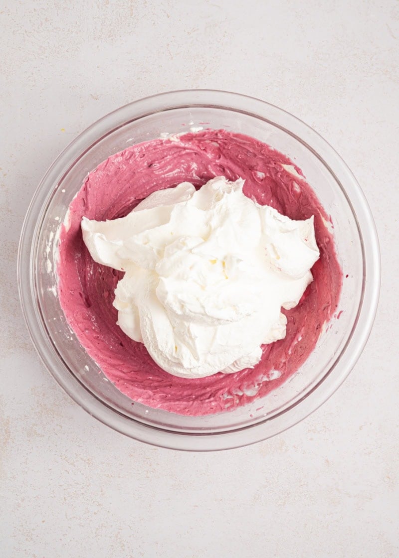 a glass bowl of blackberries filling with whipped topping.