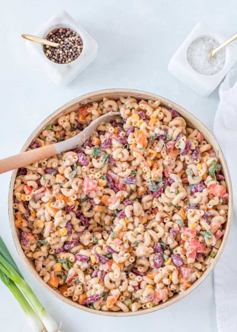 Mexican Macaroni Salad in a large wooden bowl with a wooden spoon in it.
