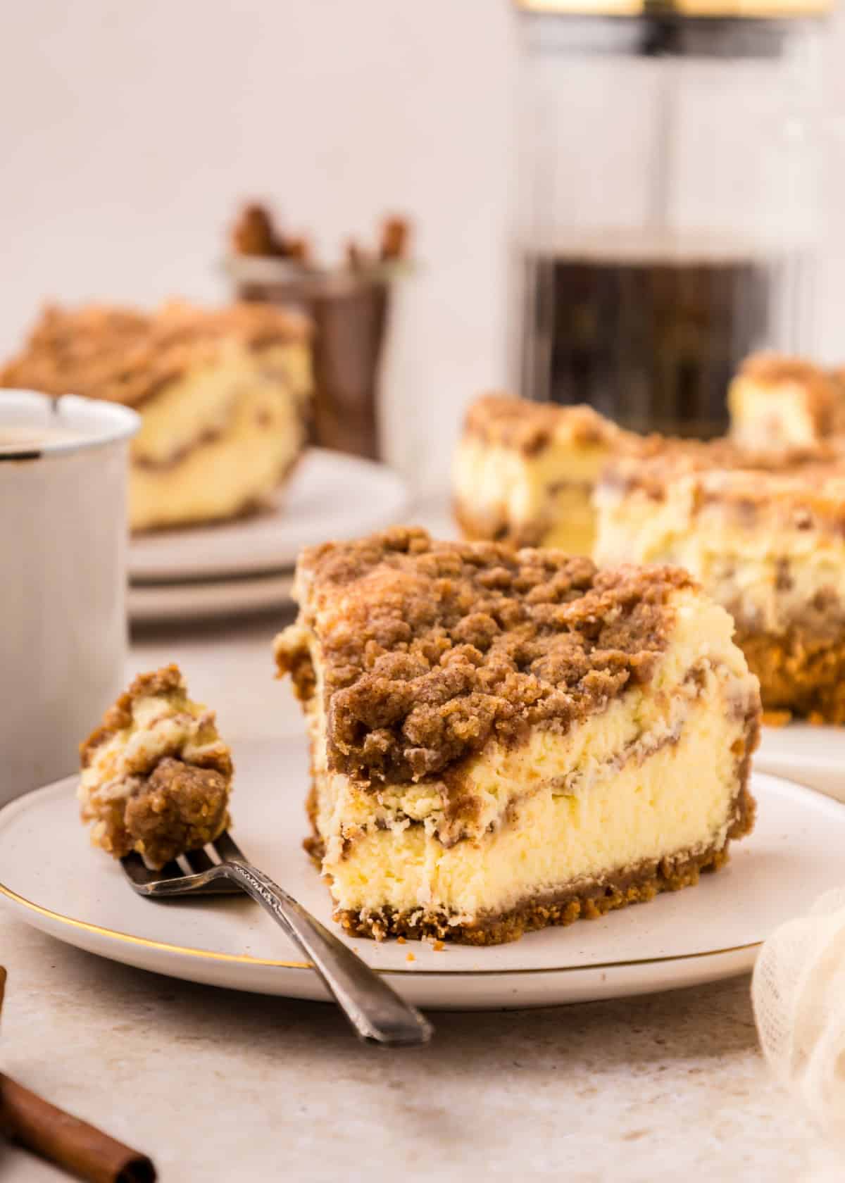 a slice of Coffee Cake Cheesecake on a white plate with a fork beside it.