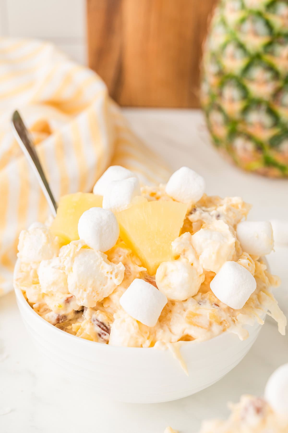 Pineapple Fluff salad in a white bowl with marshmallows and pineapple chunks on top.