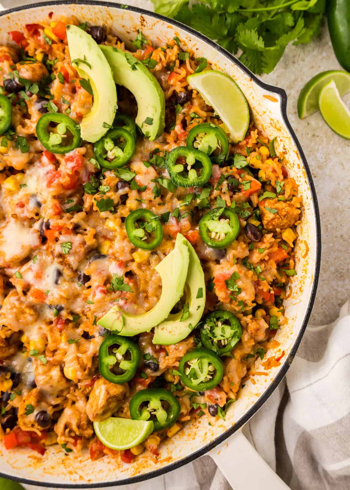Southwest Chicken Skillet in a pan with fresh avocado slices and sliced jalapeños on top.