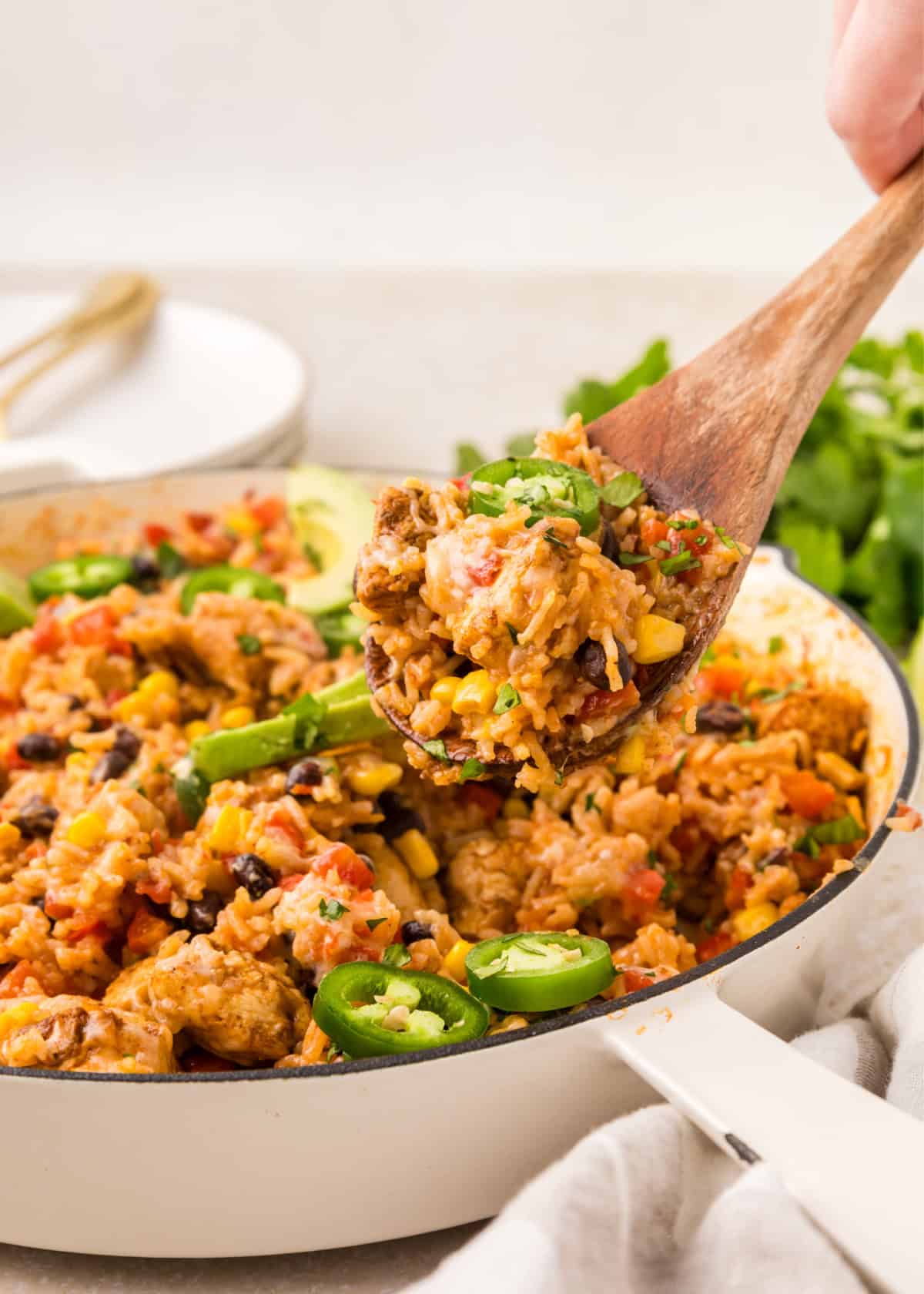 a wooden spoon taking southwest chicken skillet out of a cooking pan.