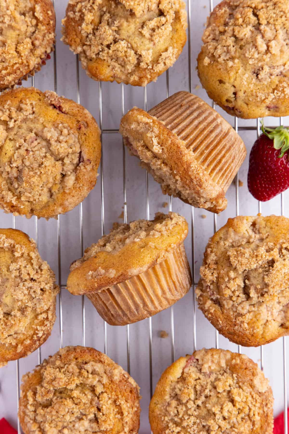 strawberry rhubarb muffins on a wire rack with fresh strawberries.