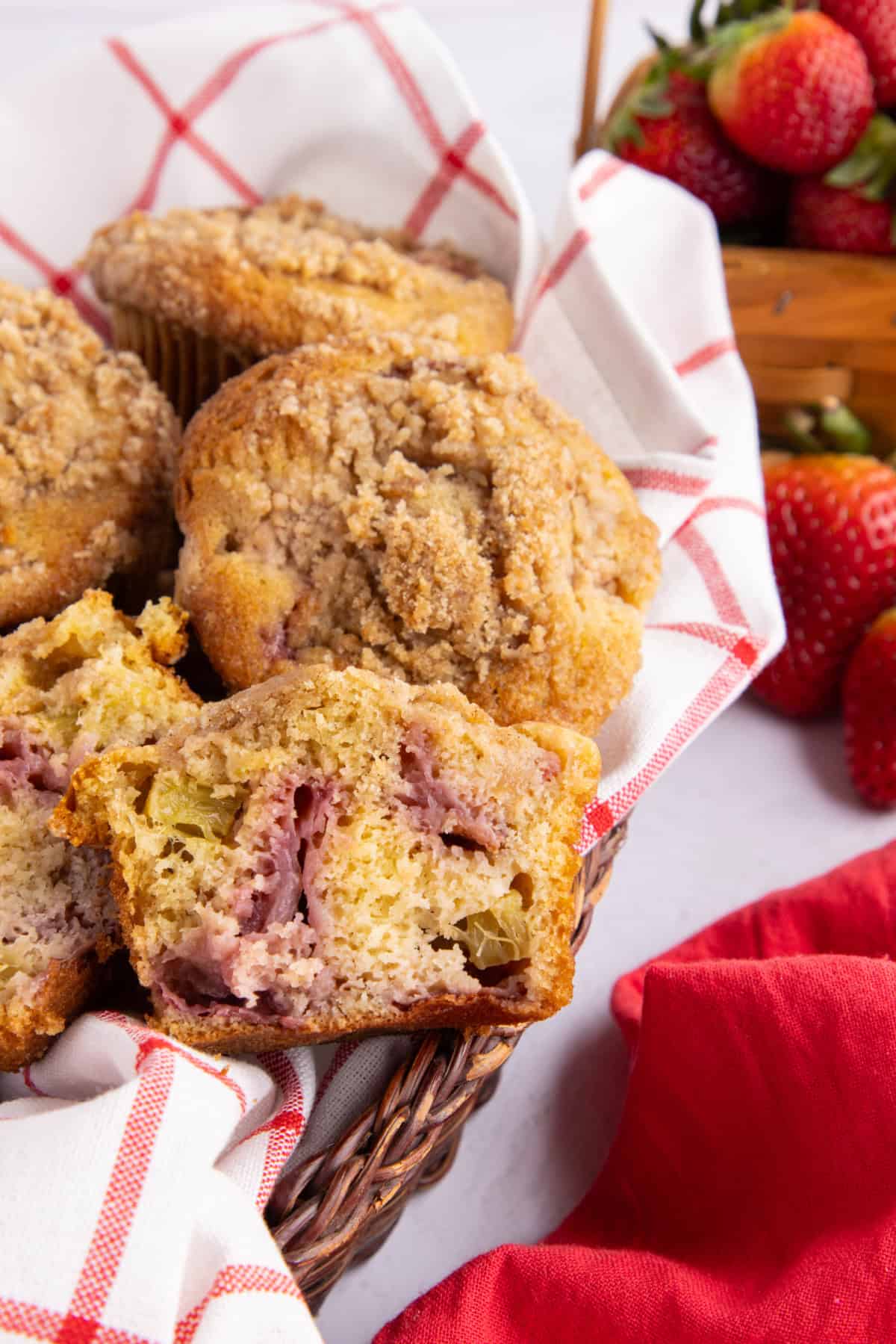 Strawberry rhubarb muffins in a basket with one cut in half.