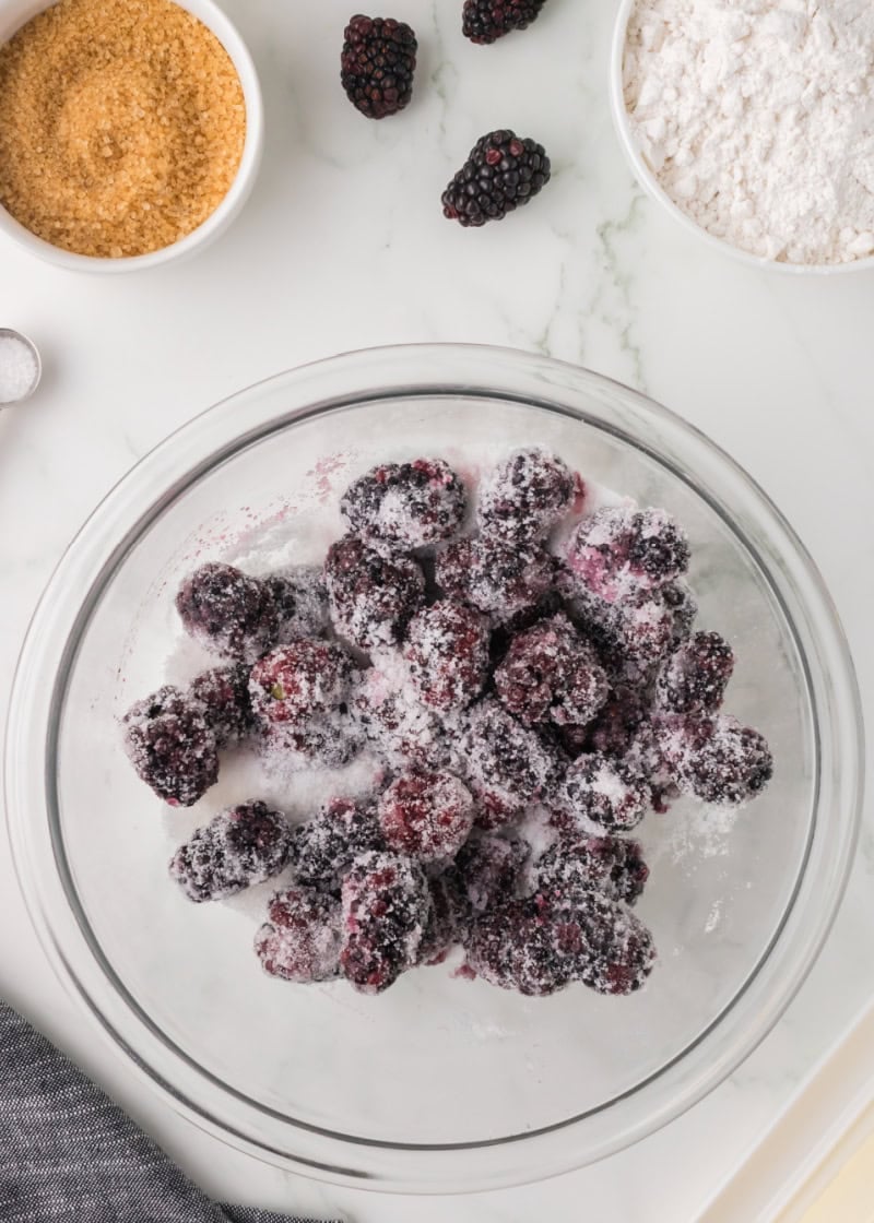 blackberries and sugar in a glass mixing bowl.