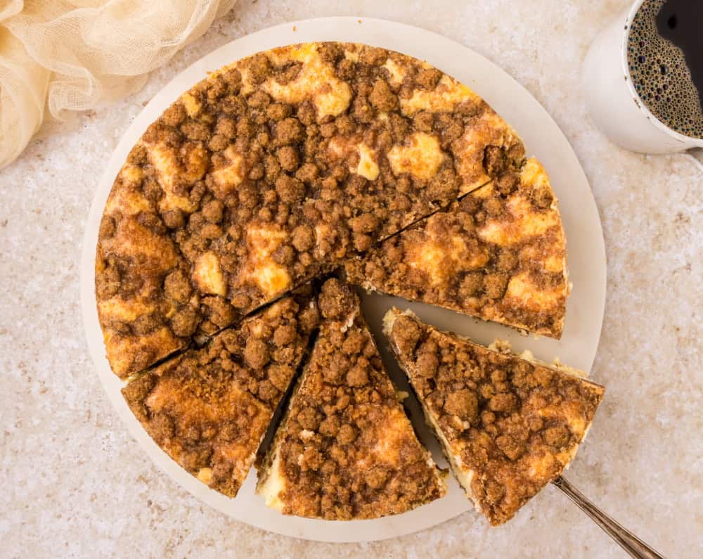 A sliced yet whole Coffee Cake Cheesecake with a piece being served out.