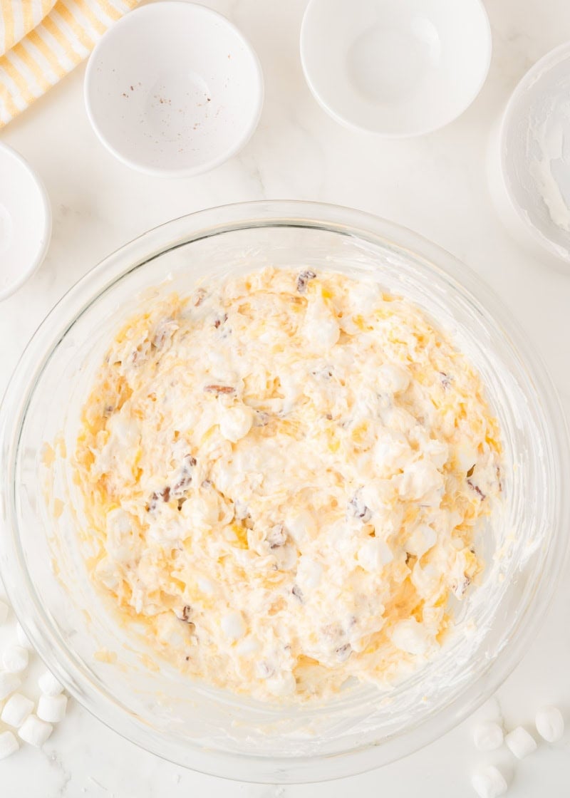 The ingredients for the pineapple fluff salad with marshmallow and pecans in a bowl.