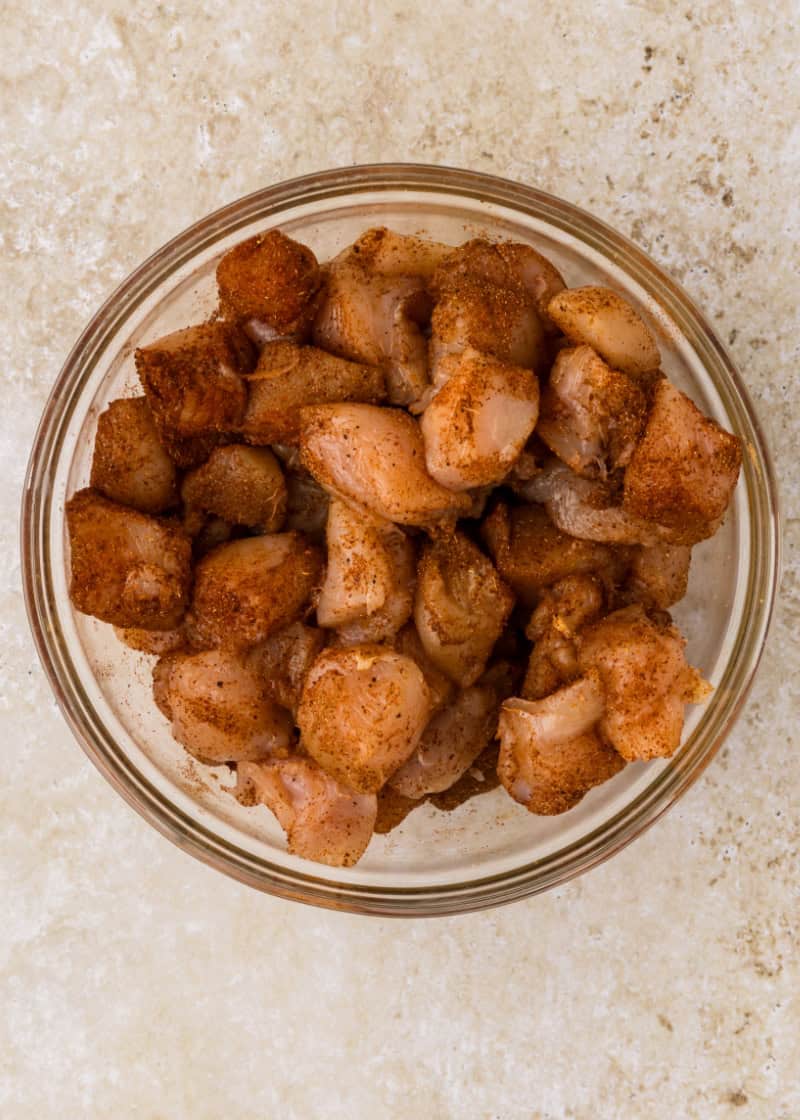 seasoned uncooked chicken cubes in a glass bowl.