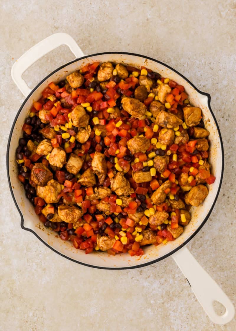 A skillet filled with chicken and corn.