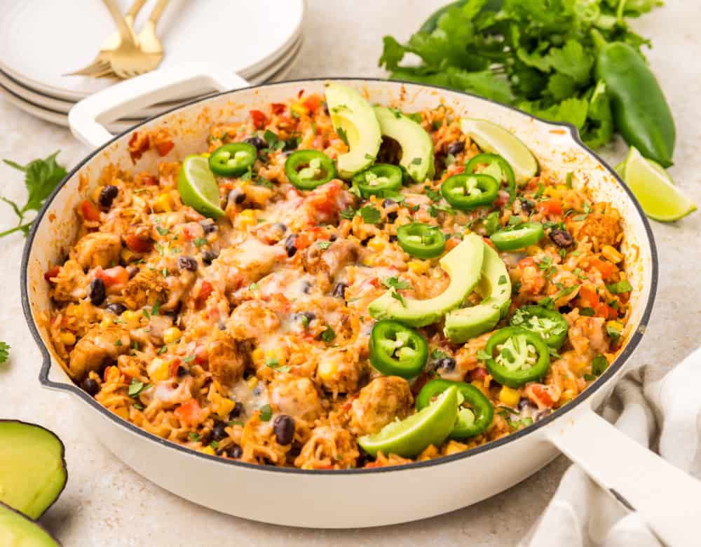 Southwest Chicken Skillet in a pan with fresh avocado slices and sliced jalapeños on top.