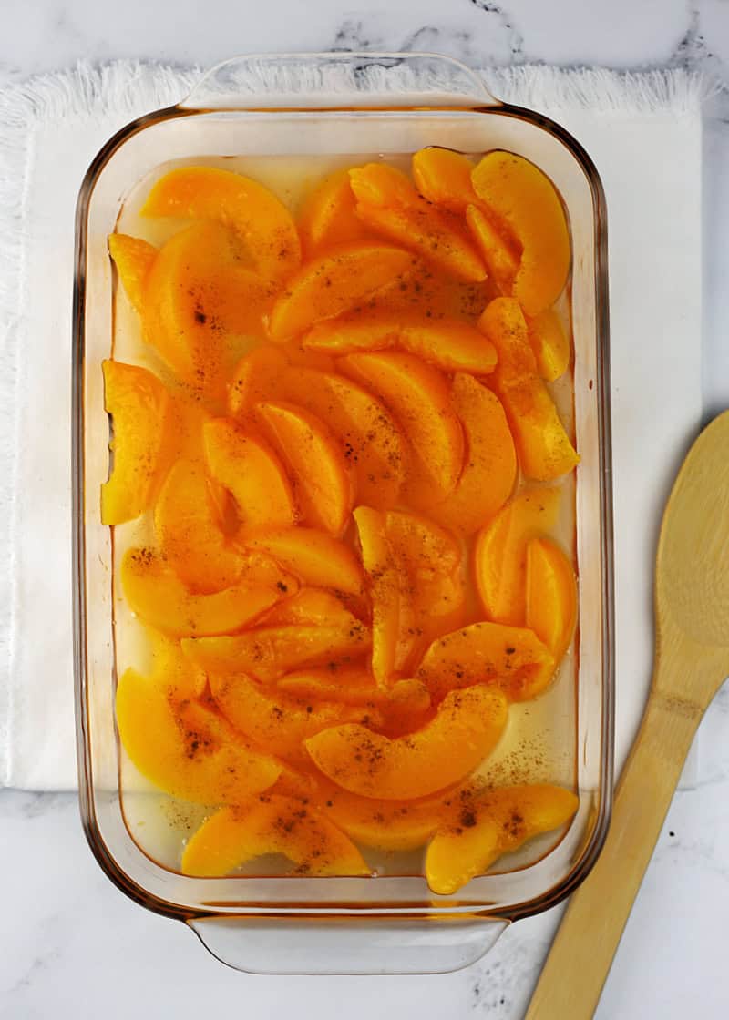 A glass casserole dish filled with sliced canned peaches.