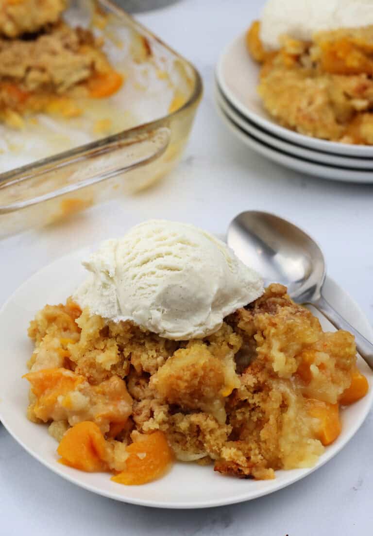Peach cobbler dump cake with vanilla ice cream on top.