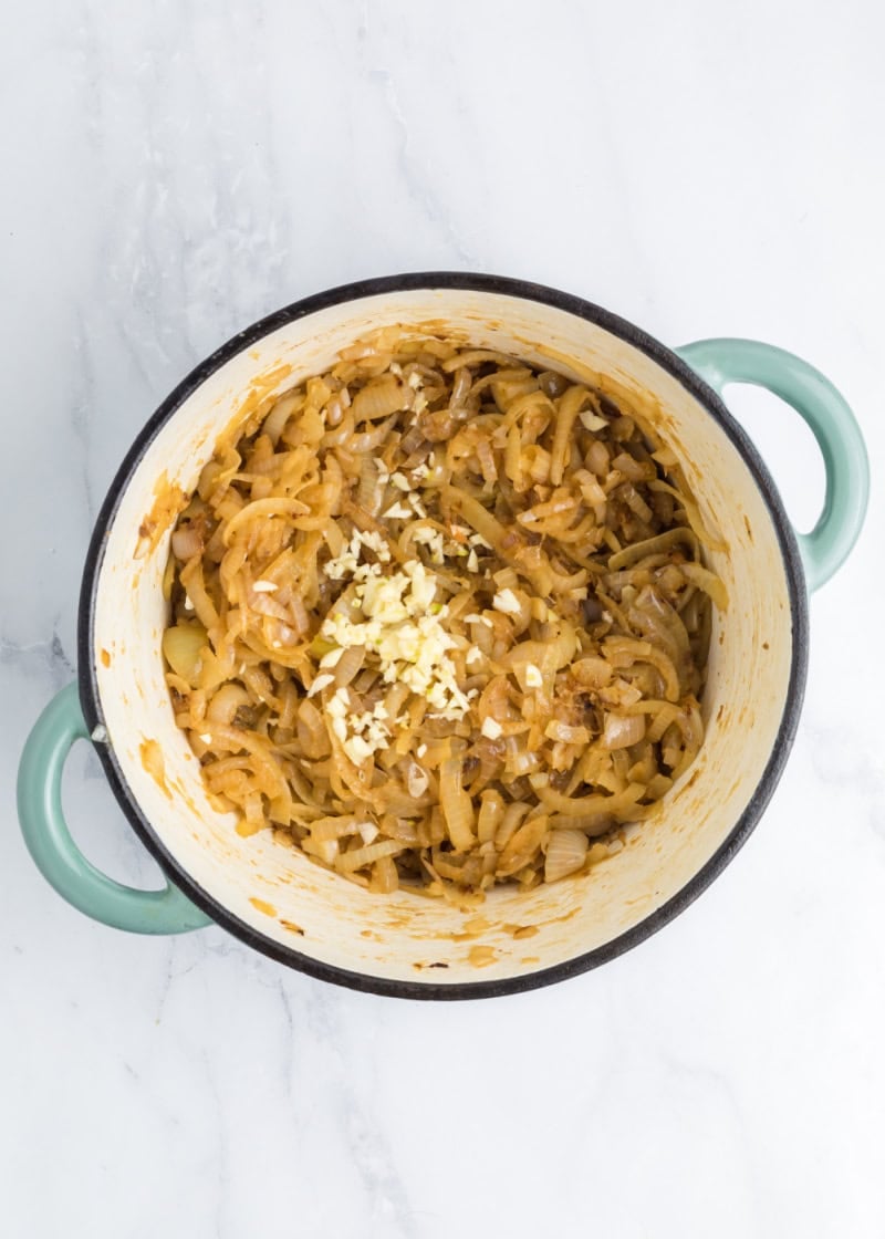 a dutch oven dish with cooked onions and garlic.