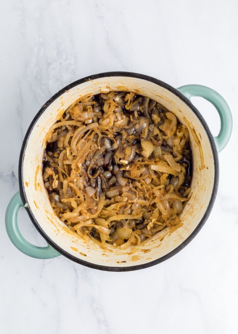 A pan with cooked onion slices and broth in it