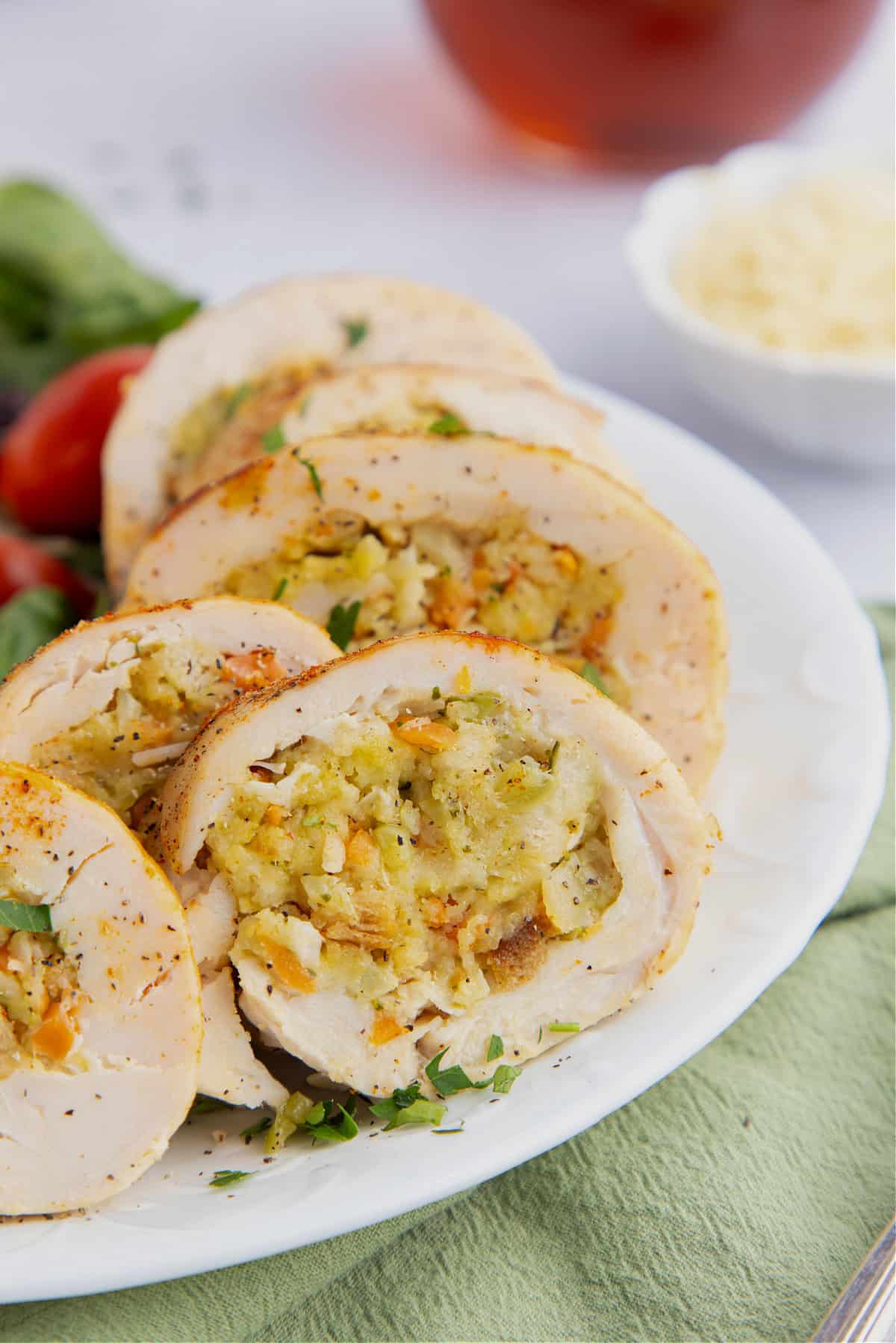 Sliced piece of stuffed chicken breast stuffed with stuffing on a white plate.