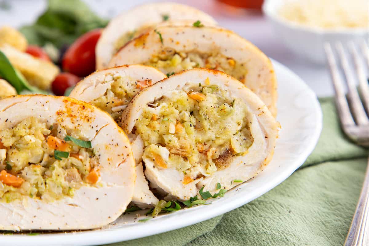 Stuffed chicken breast stuffed with stuffing on a white plate.