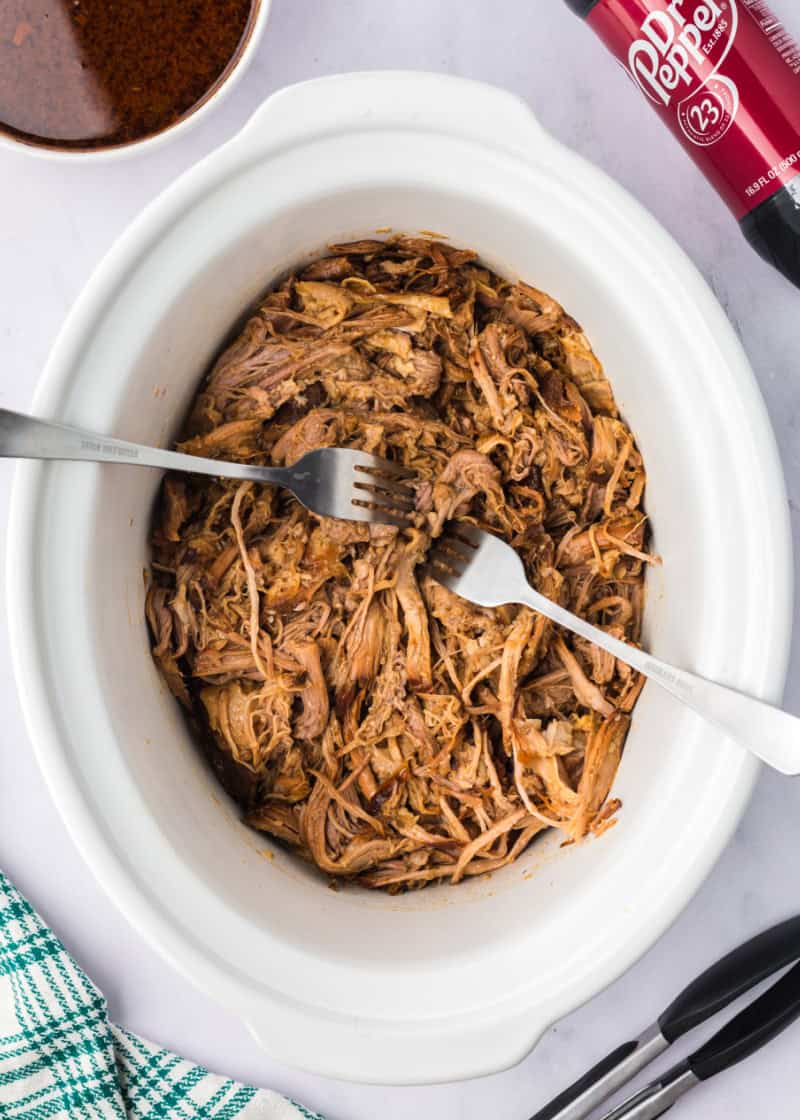 shredding pork in a slow cooker with two forks.