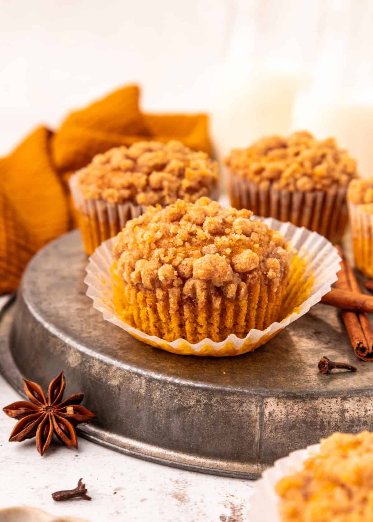 Pumpkin Streusel Muffins on a plate with the paper liner peeled off the sides.