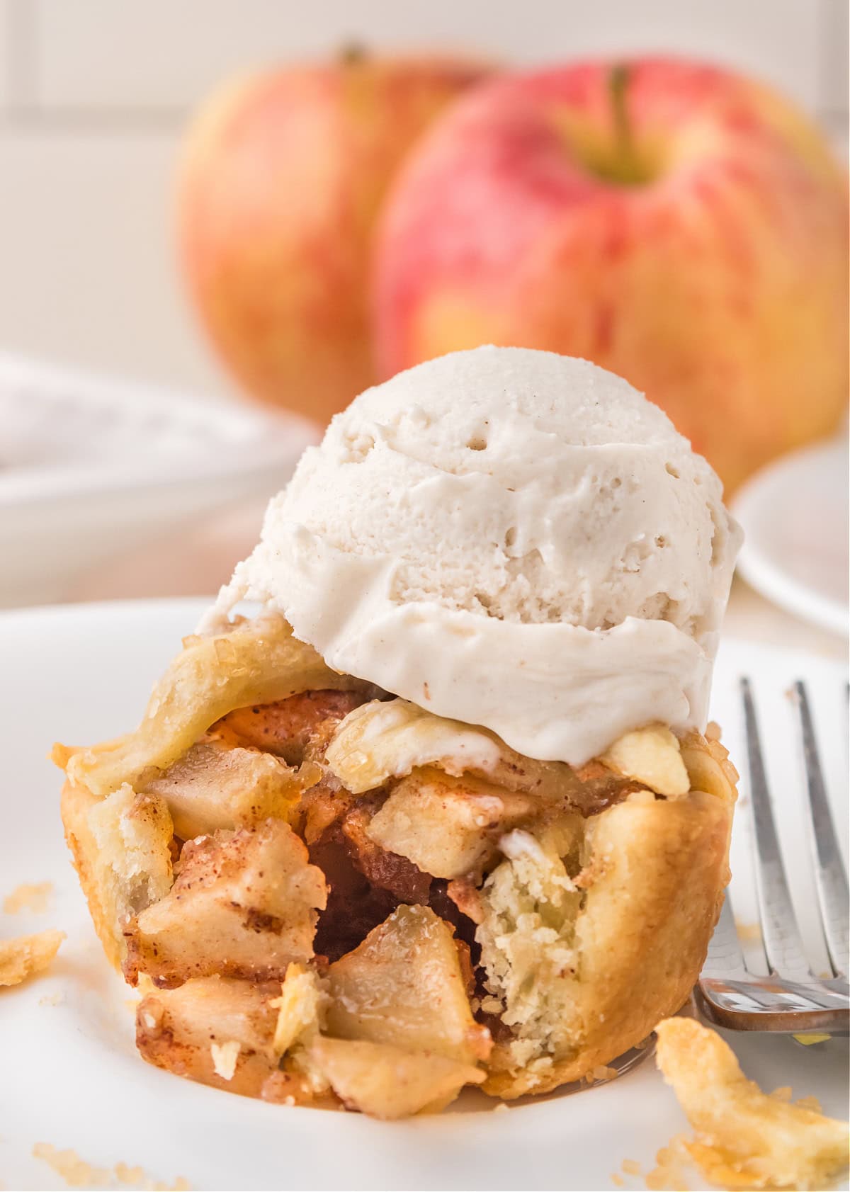 mini apple pie on a plate with a scoop of vanilla ice cream on top.